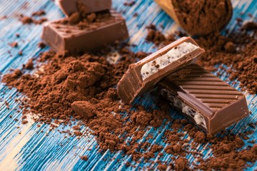 Detail of chocolate with creamy filling on blue board with cocoa