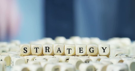 Slow motion macro of the word "Strategy" of the wooden letter blocks . Concept of financial market and future of stock market business. - Powered by Adobe