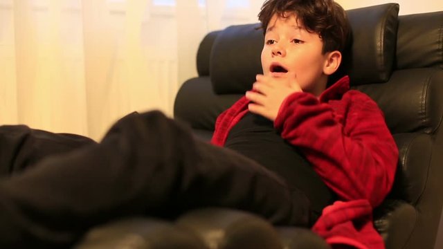 Excited young boy child lying on a sofa and watching horror movie at home