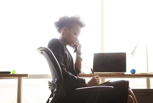 Businesswoman Using Landline And Making Notes