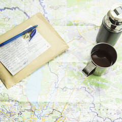Fototapeta na wymiar Map & Travel. thermos mug camp, an envelope and a postcard from your trip. on the map background