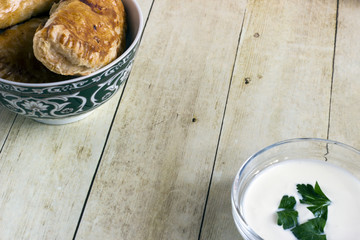 Empanadas in green plate on light wood background