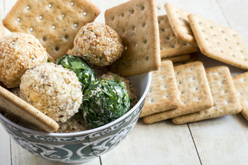 Cheeseballs with crackers on light wood background