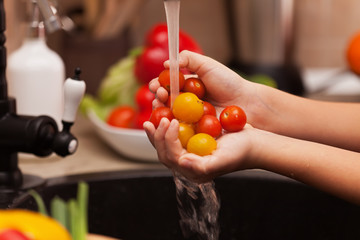 Preparing a healthy salad - child hands washing cherry tomatos, shallow depth