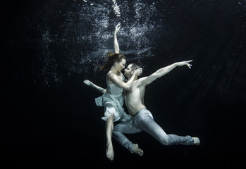 Fototapeta na wymiar Young couple dancing underwater