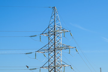 Supports high-voltage power lines against the blue sky