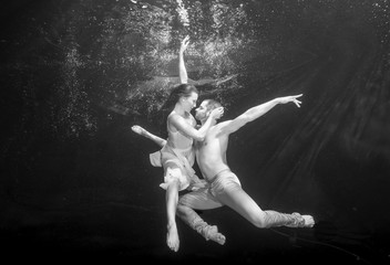 Yong couple of ballet dancers dacing underwater