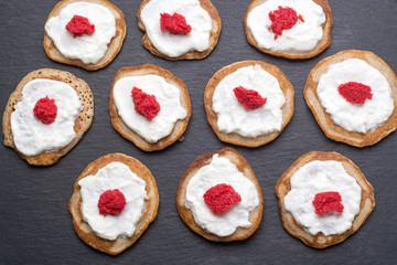 Obraz na płótnie Canvas Homemade blinis with sour cream and red caviar