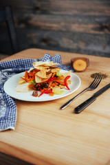 Mexican tortilla chips with salad on a wooden table.