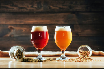 Two glasses of beer on a wooden table grains