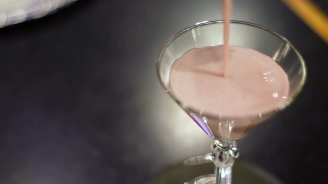 Raspberry martini being poured into a glass.