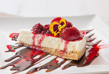 A slice of cheesecake with strawberry and raspberry sauce.