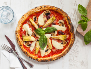 Pizza with tomato, mozzarella cheese, artichokes, mushrooms and basil.