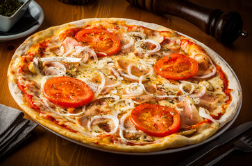 Pizza with tomato, cheese, bacon, onion and tomato.