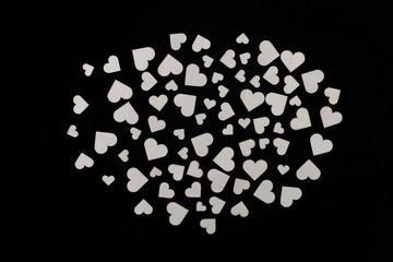 Wooden hearts of various sizes spread out on a black background