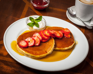 Breakfast with pancakes, syrup and strawberries