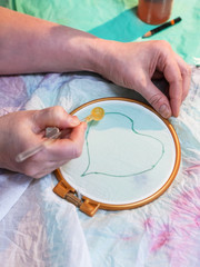 artist draws contour of heart on batik