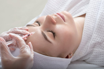 Young woman gets beauty facial injections in salon.