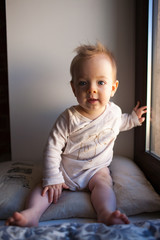 Portrait of a little boy who is sitting in the window and smiling. emotions concept.