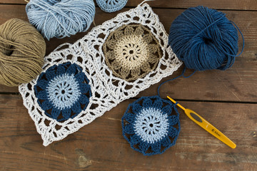 Granny square crochet motifs and yarn balls on the brown wooden background