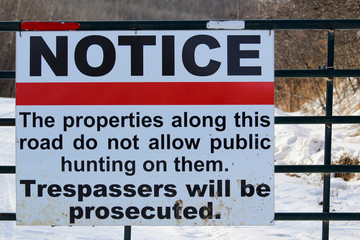 No Trespassing or Hunting Sign on a Gate