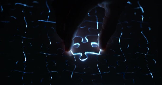 A creative completes the black or white light puzzle putting the last missing piece. Concept: cooperation, teamwork, creativity, and access solution.