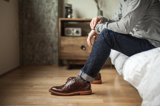 Man Sitting On Bed In Jeans And Shoes 