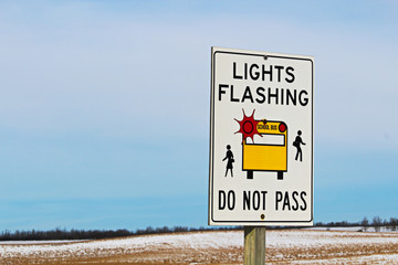 Lights Flashing School Bus Sign Along a Rural Highway