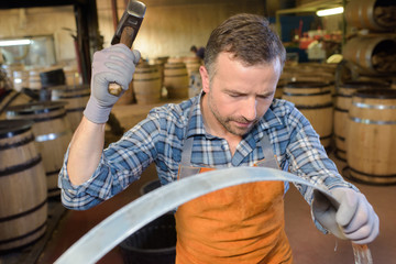 wood barrels production cooper using hammer and tools in workshop © auremar