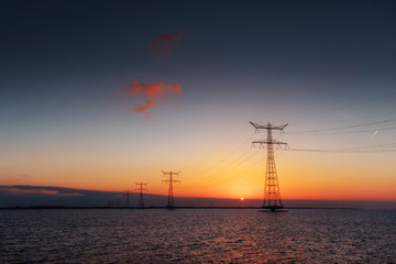 Fototapeta na wymiar electric line above water during a fantastic sunset