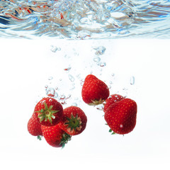 fresh strawberry dropped into water with splash on white backgro
