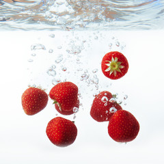 fresh strawberry dropped into water with splash on white backgro