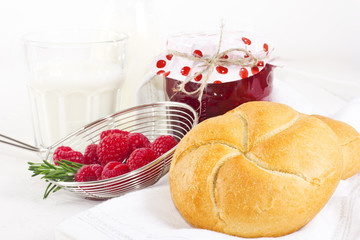 Homemade raspberry jam with milk and fresh bred for breakfast on white