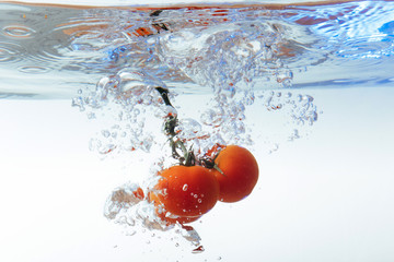Fototapeta na wymiar Fresh cherry tomatoes with water splash isolated on white backgr