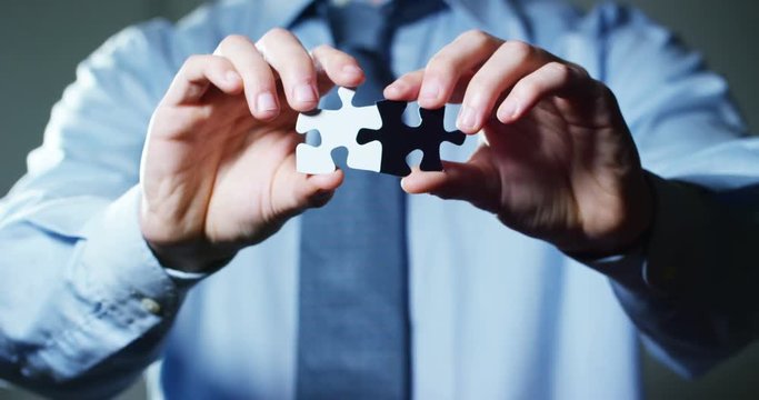 A creative completes the black or white light puzzle putting the last missing piece. Concept: cooperation, teamwork, creativity, and access solution.