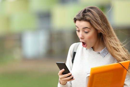 Astonished student receiving news on a smart phone