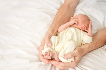 newborn baby in father's hands, indoor portrait