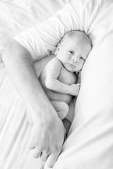 young loving father with newborn twin babies, indoor portrait