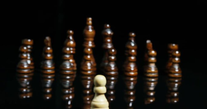 Macro shot of chess, in which a white piece tackles all the black pawns. Concept: challenge, one against all, team success sport.