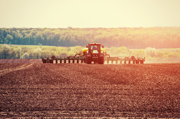 Fototapeta premium Tractor plowing farm field in preparation for spring planting