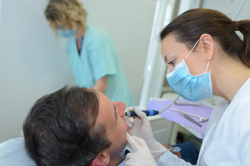 Dentist using implement on patient's teeth