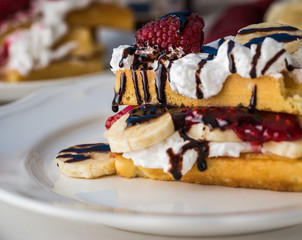 Belgian waffles with raspberries and double cream on white plate.
