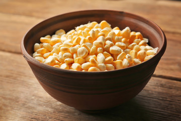 Bowl with corn seeds on wooden rustic table, closeup