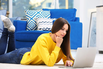 Young woman working on laptop at home, interior background