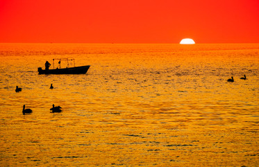 Obraz premium Hot morning silhouette of fishing boat off Loreto on the Sea of Cortez symbolic of global warming 