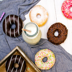 Bottle of milk and colorful donuts with chocolate and icing, selective focus