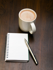 Blank notebook, pen and cup of coffee on wooden brown background, copy space.