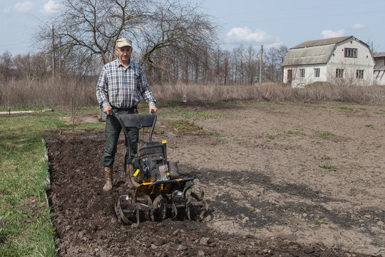 Man loosens the soil cultivator