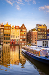 Naklejka premium Traditional old buildings and boats at sunset in Amsterdam, Netherlands.