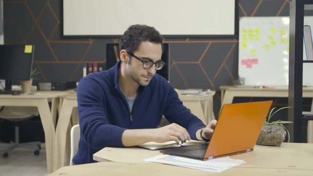Creative man in glasses using laptop at workplace